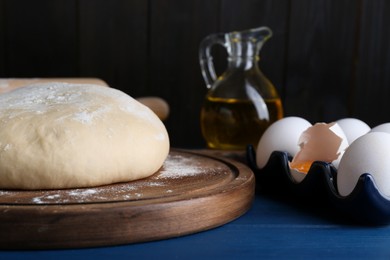 Fresh yeast dough and ingredients on blue wooden table, closeup