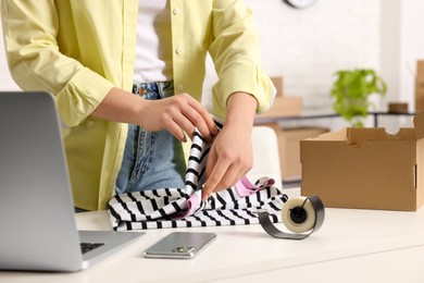 Seller packing clothes at workplace, closeup. Online store