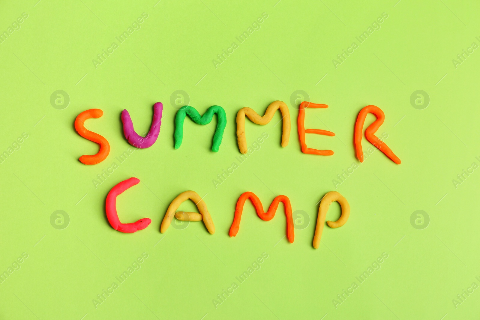 Photo of Words SUMMER CAMP made from modelling clay on color background, top view