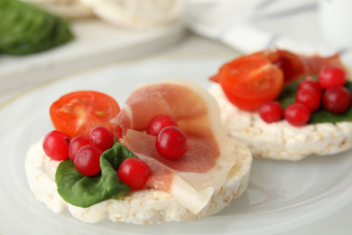 Photo of Puffed rice cakes with prosciutto, berries and basil on plate, closeup