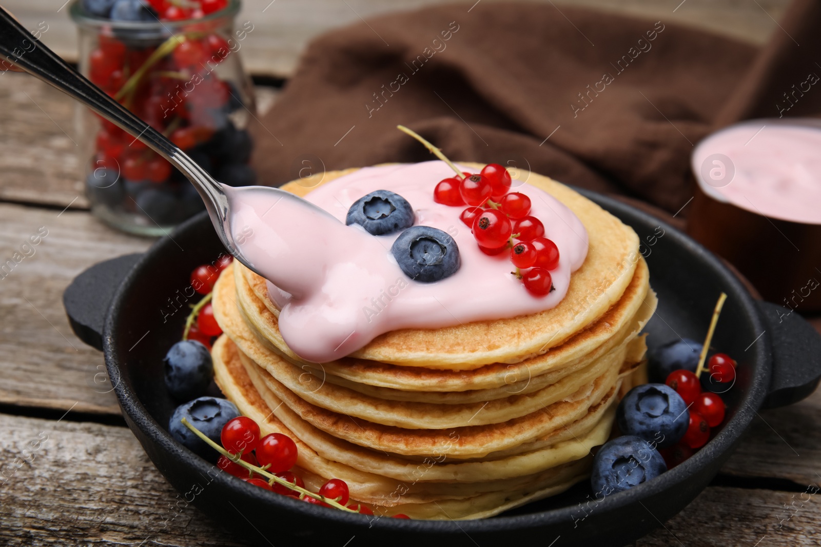 Photo of Tasty pancakes with natural yogurt, blueberries and red currants on wooden table