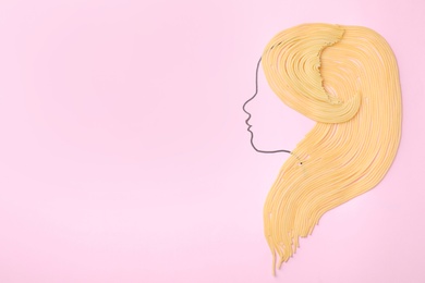 Photo of Pasta as hair for drawn girl's face on pink background, top view