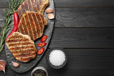 Photo of Delicious grilled pork steaks with spices on dark wooden table, flat lay. Space for text