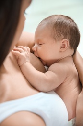 Photo of Young woman breastfeeding her baby on light background, closeup