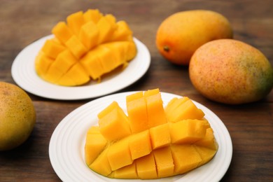 Delicious ripe cut and whole mangos on wooden table