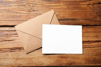 Photo of Blank sheet of paper and letter envelope on wooden table, top view. Space for text