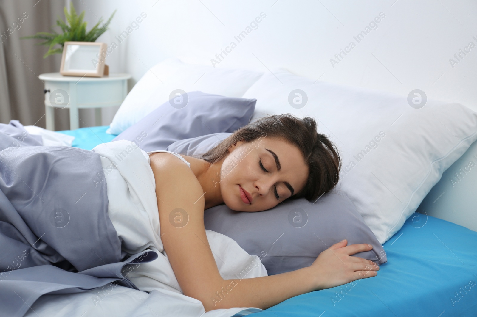 Photo of Young woman sleeping on soft pillow at home. Bedtime