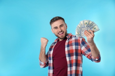 Portrait of happy young man with money on color background. Space for text