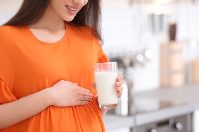 Beautiful pregnant woman drinking milk in kitchen