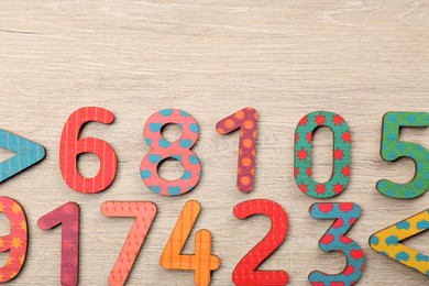 Photo of Colorful numbers and mathematical symbols on light wooden table, flat lay. Space for text