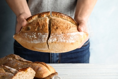 Photo of Man holding whole wheat bread over table, closeup