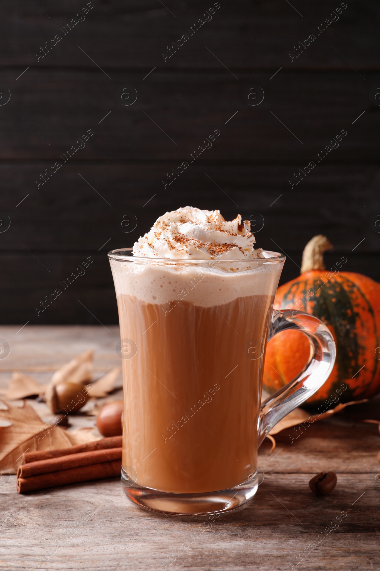 Photo of Glass cup with tasty pumpkin spice latte on wooden table