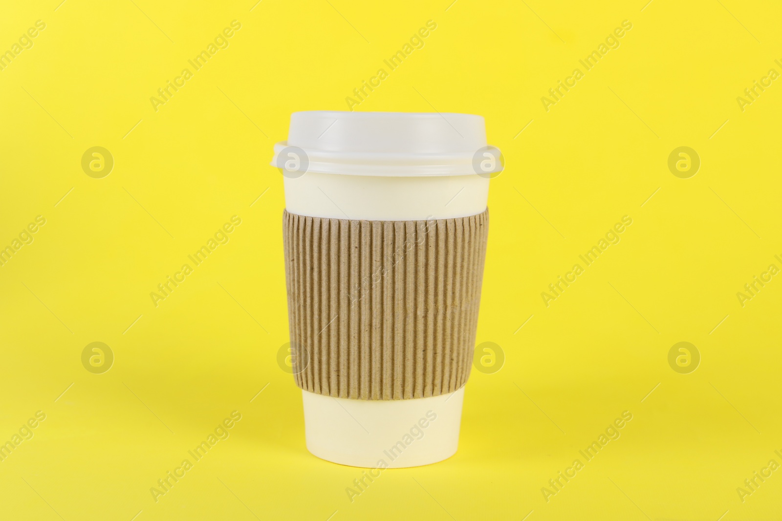 Photo of Paper cup with plastic lid on yellow background. Coffee to go