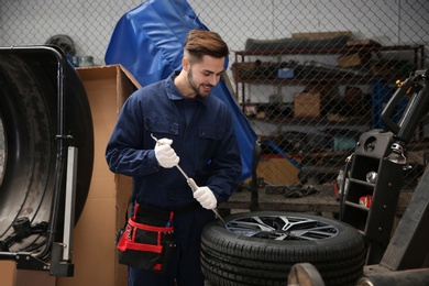 Photo of Technician working with car wheel at automobile repair shop