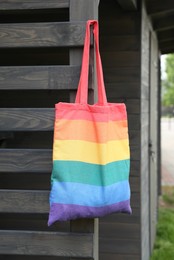 Photo of Rainbow bag hanging on wooden building outdoors. LGBT pride