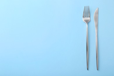 Photo of Stylish cutlery on light blue table, top view. Space for text