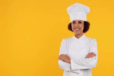 Photo of Portrait of happy female chef in uniform on orange background. Space for text