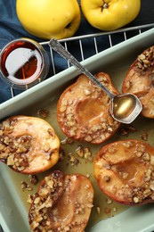 Tasty baked quinces with nuts and honey in dish on table, flat lay