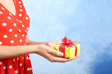 Photo of Woman holding beautifully wrapped gift box on color background