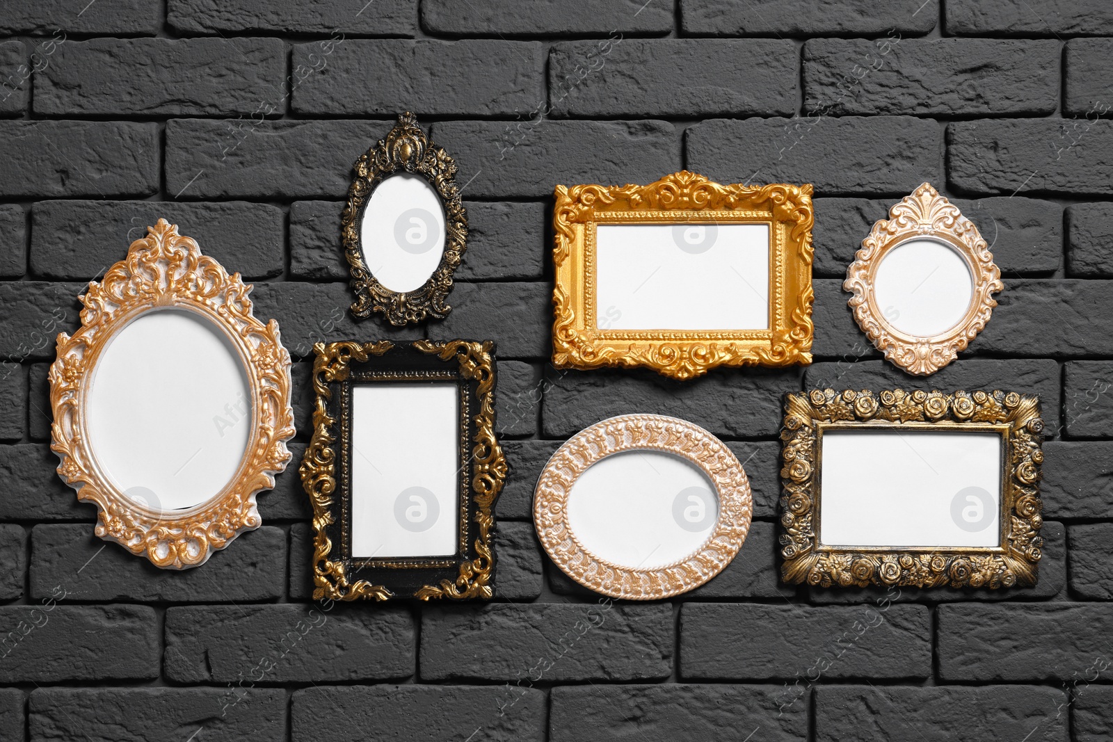 Photo of Empty vintage frames hanging on dark brick wall. Mockup for design