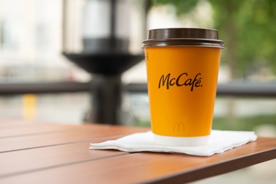 WARSAW, POLAND - SEPTEMBER 04, 2022: McDonald's hot drink on wooden table outdoors, space for text
