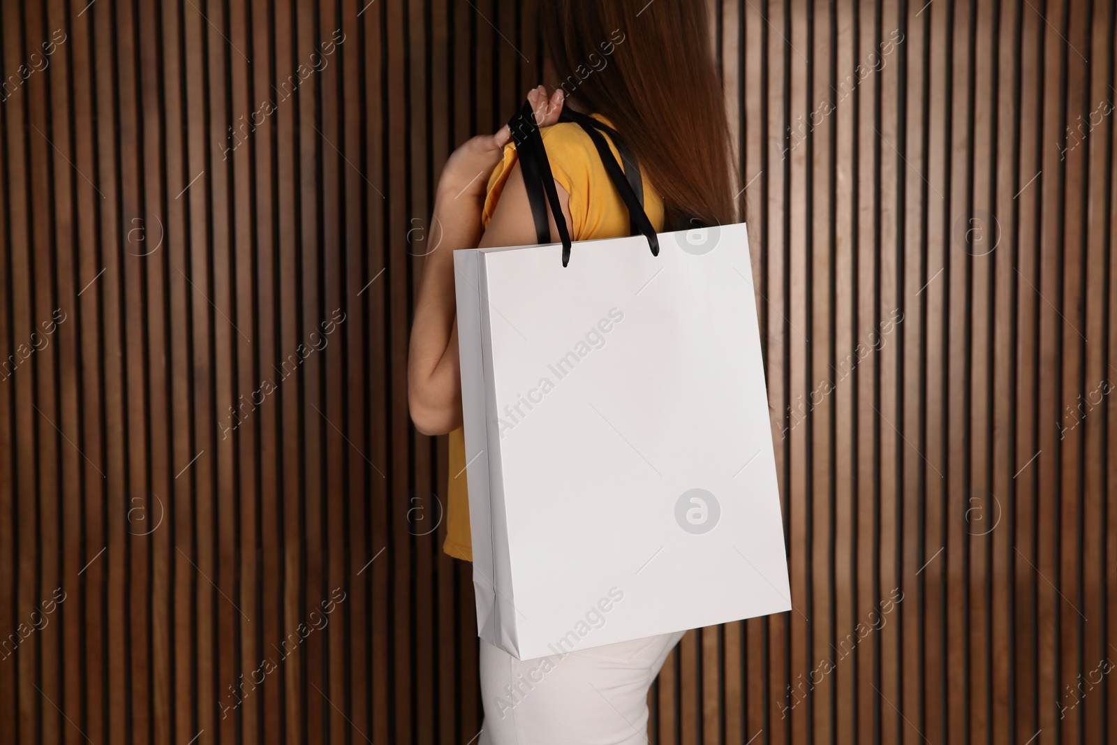 Photo of Woman with paper shopping bag on wooden background. Mock up for design