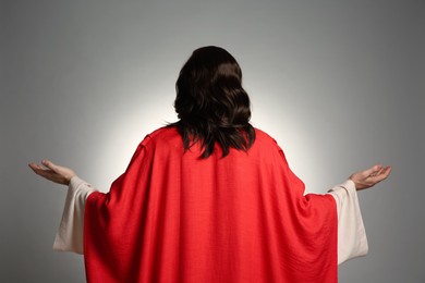 Photo of Jesus Christ with outstretched arms on light grey background, back view