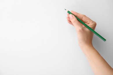 Photo of Woman with green pencil on white background, closeup. Space for text