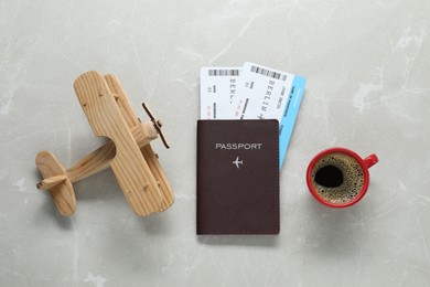 Flat lay composition with passport, tickets, cup of coffee and wooden plane model on light marble table. Business trip