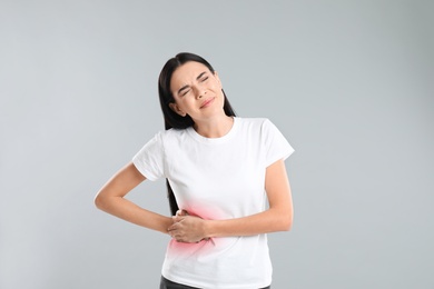 Woman suffering from liver pain on grey background