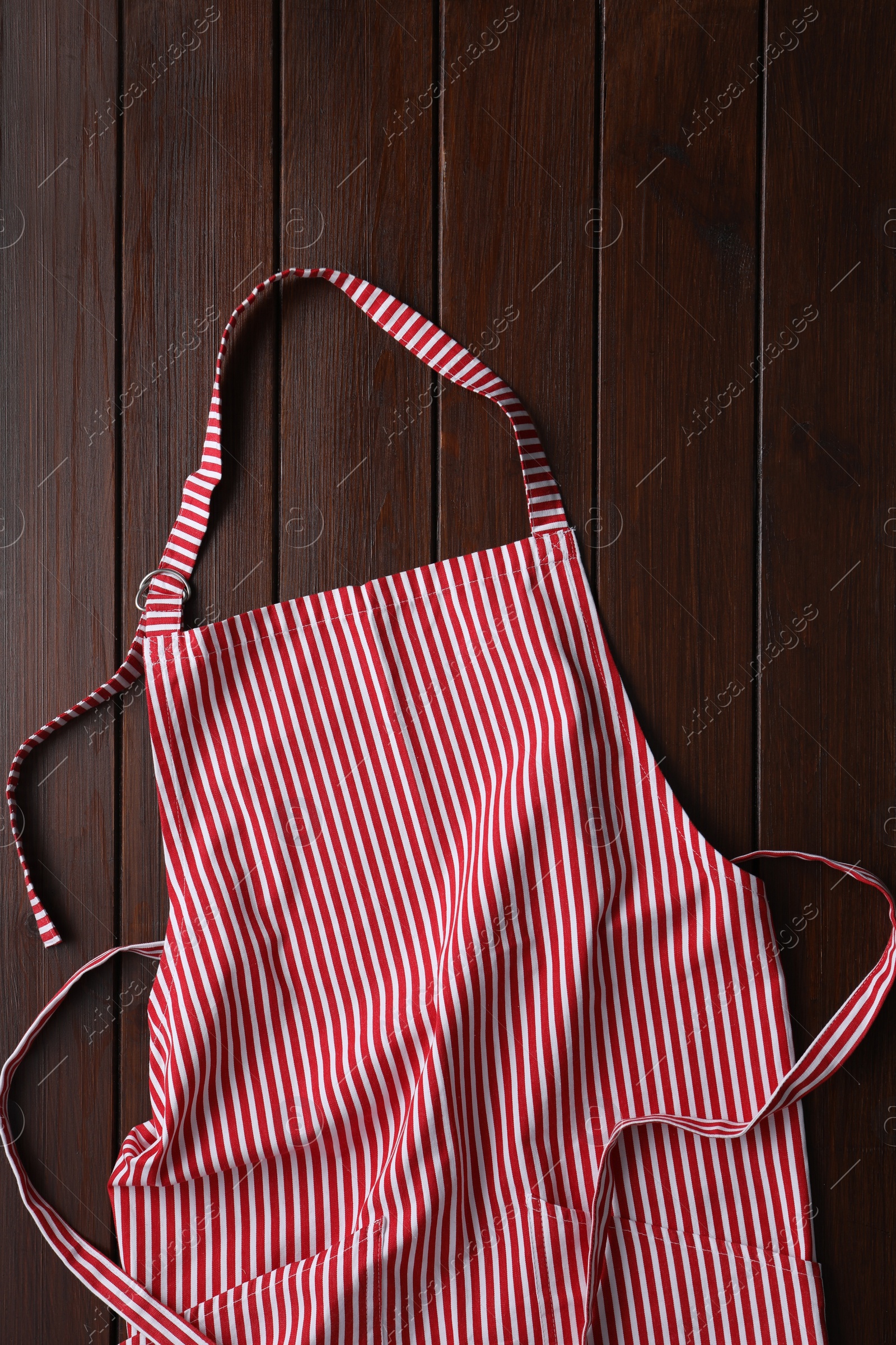 Photo of Striped apron on wooden table, top view