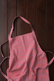 Photo of Striped apron on wooden table, top view