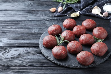 Photo of Many fresh raw meatballs on black wooden table, space for text