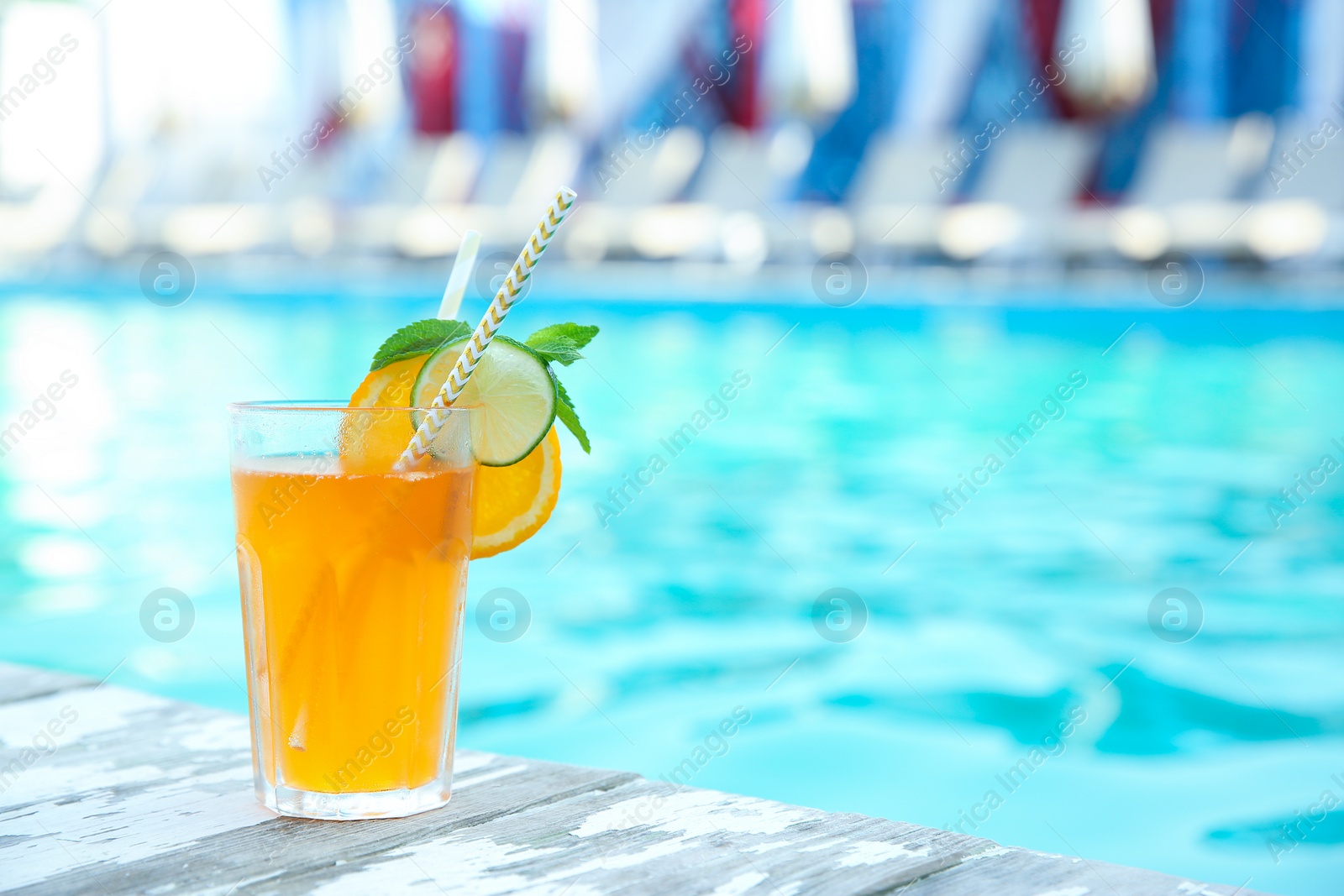 Photo of Refreshing cocktail near outdoor swimming pool on sunny day. Space for text