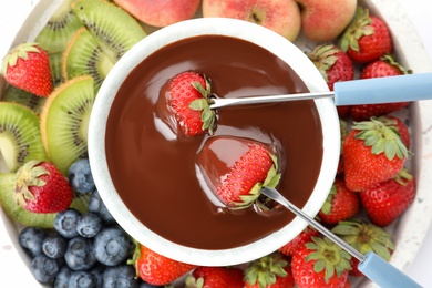 Photo of Dipping strawberries into fondue pot with chocolate, top view