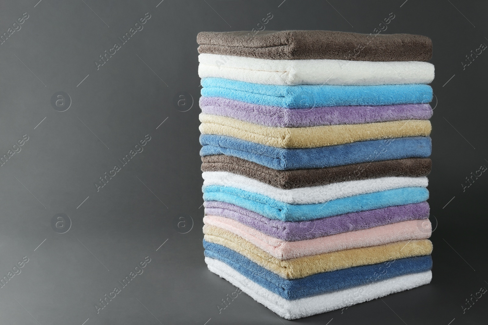 Photo of Different fresh soft terry towels on grey background