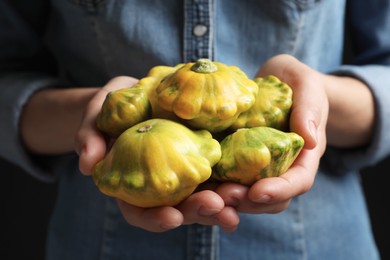 Photo of Woman with fresh ripe pattypan squashes on black background, closeup
