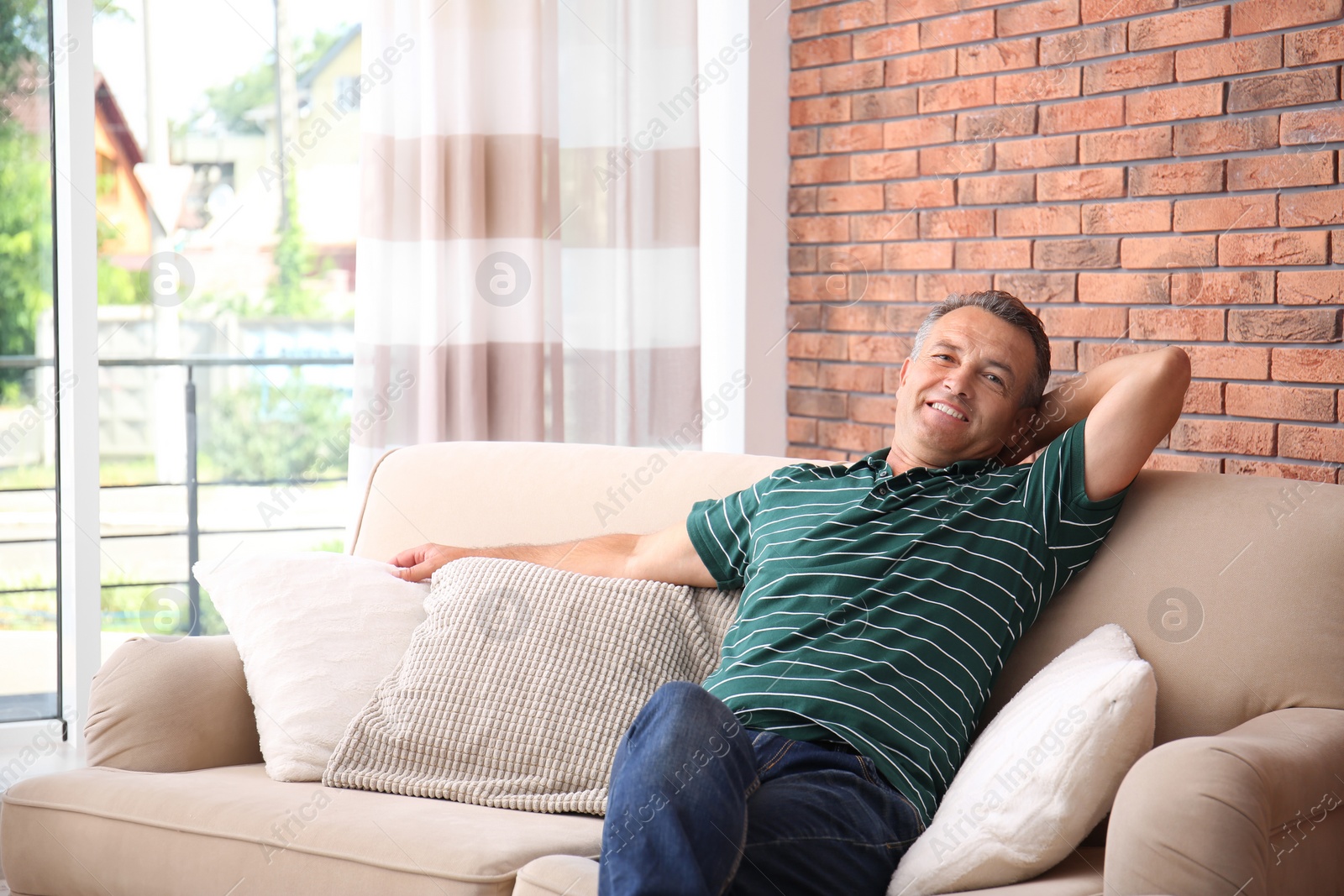 Photo of Man relaxing on sofa with comfortable pillows at home