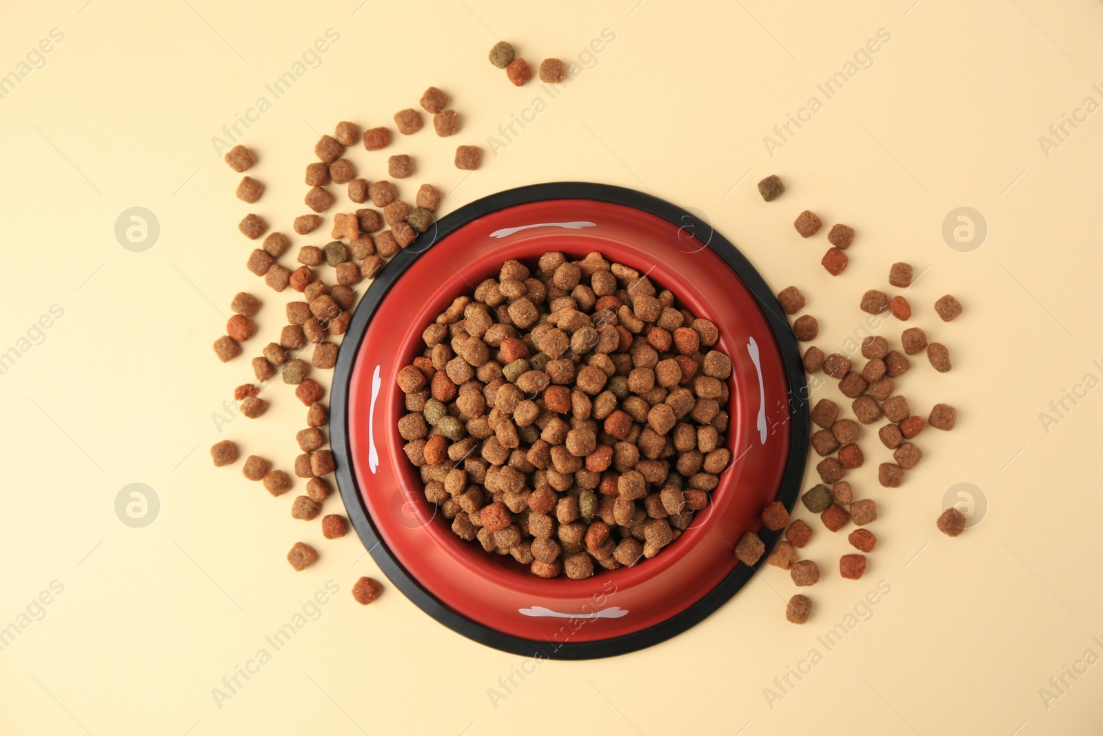 Photo of Dry dog food and feeding bowl on beige background, flat lay