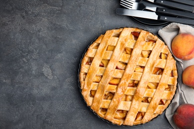 Photo of Delicious peach pie and fresh fruits on grey table, flat lay. Space for text