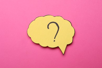 Photo of Paper speech bubble with question mark on pink background, top view