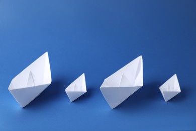 Photo of Handmade paper boats on blue background. Origami art