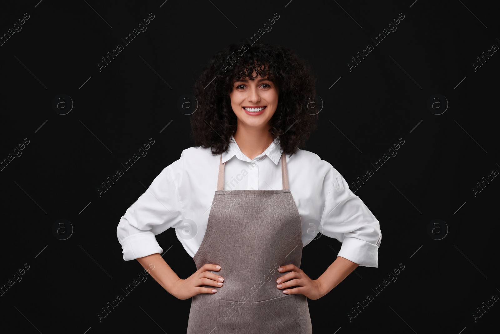 Photo of Happy woman wearing kitchen apron on black background. Mockup for design