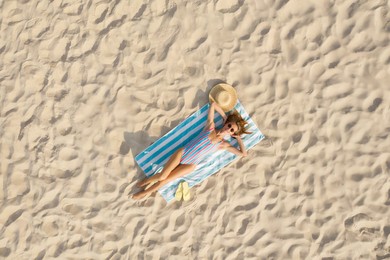 Woman sunbathing on beach towel at sandy coast, aerial view