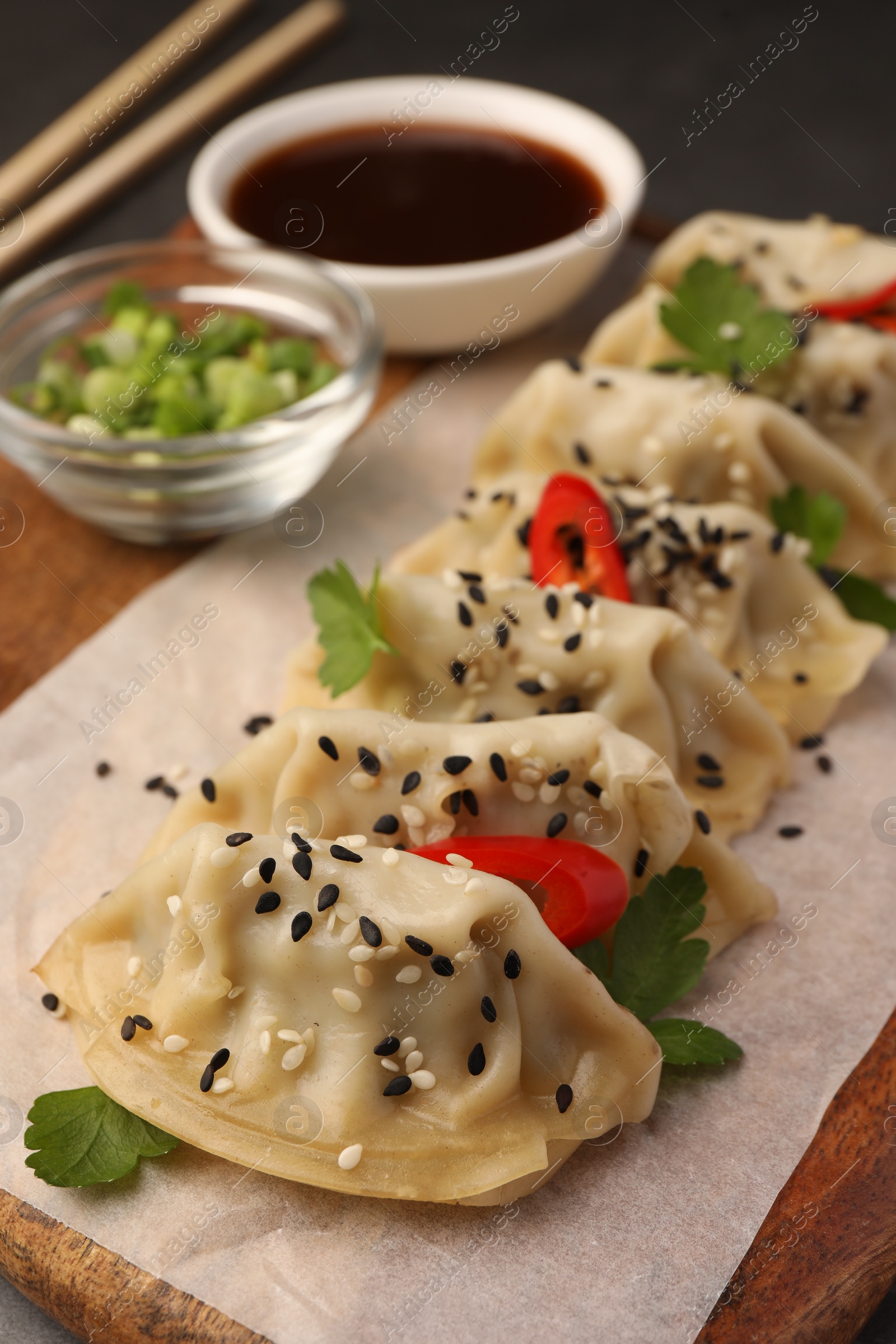 Photo of Delicious gyoza (asian dumplings) with sesame seeds on wooden board