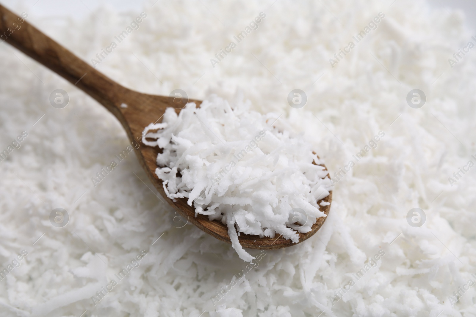 Photo of Fresh coconut flakes and wooden spoon, closeup