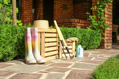 Photo of Wooden crates and gardening tools on stone path at backyard