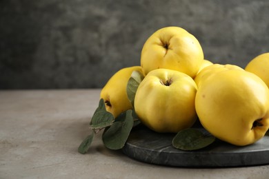 Fresh ripe organic quinces with leaves on grey table. Space for text