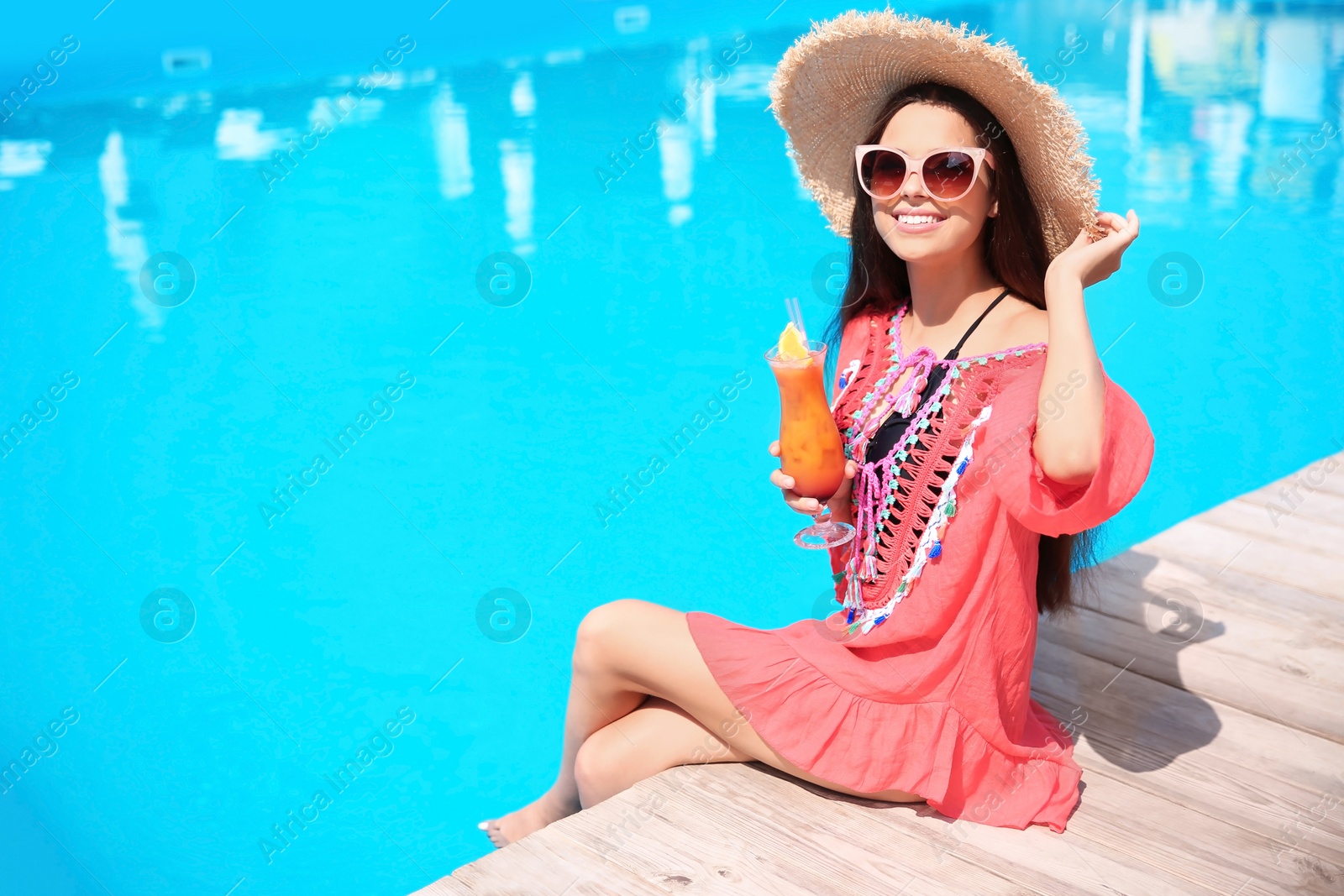 Photo of Beautiful young woman with cocktail sitting near swimming pool