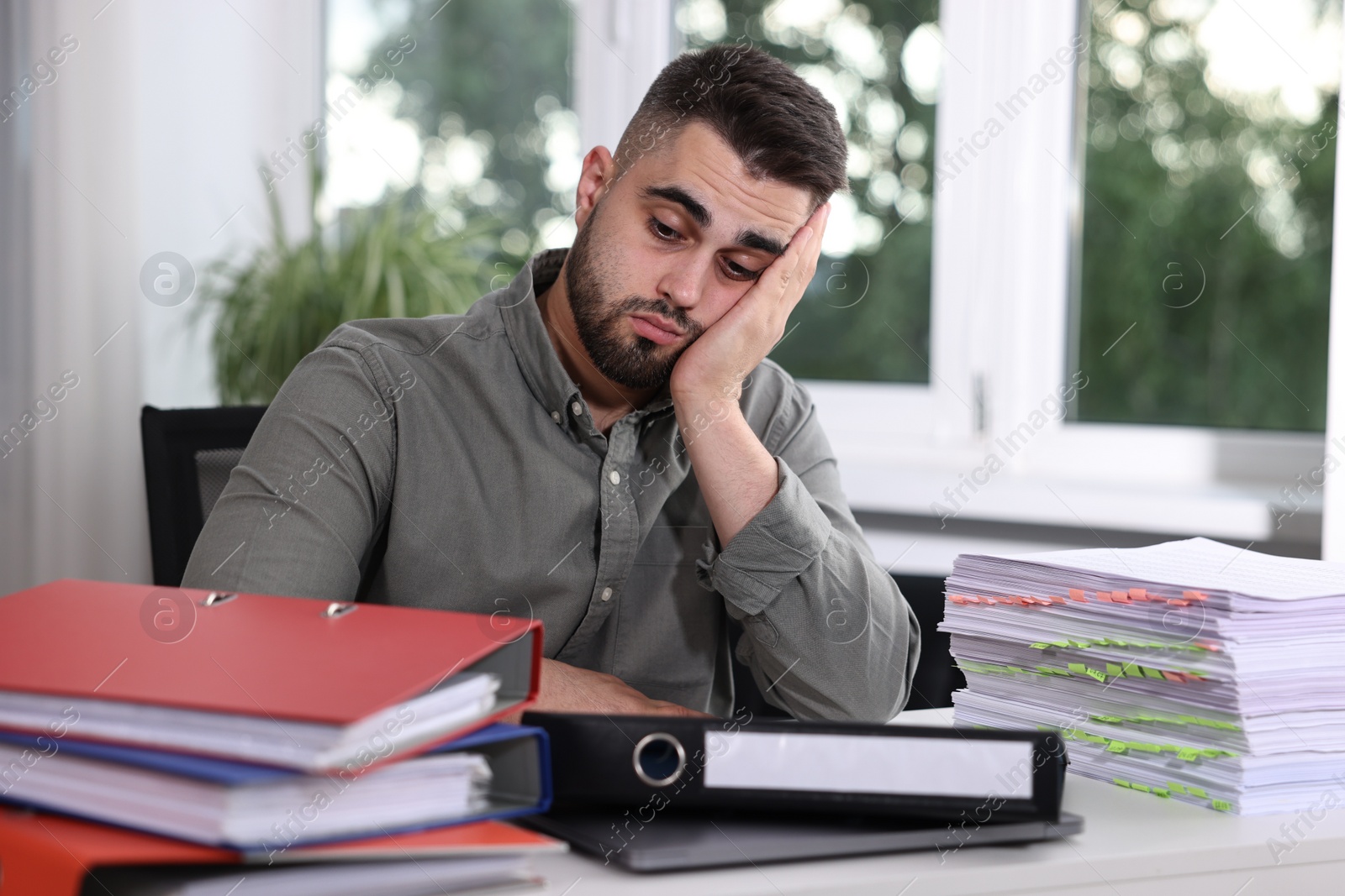 Photo of Overwhelmed man sitting at table with documents in office